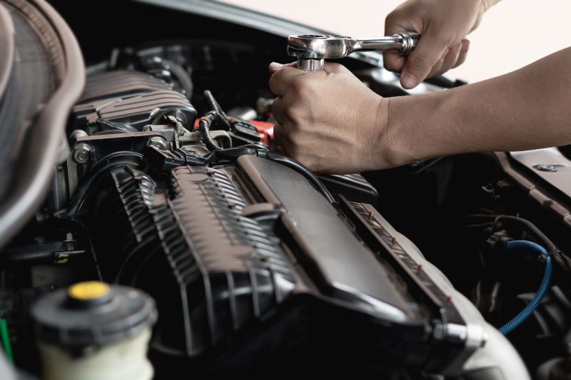 A photo of a person working under the hood of a car.