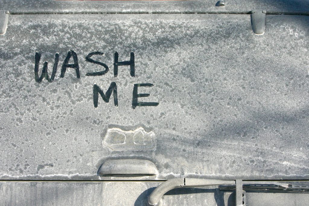 The words "Wash me" written on a car covered in salt that needs a clean