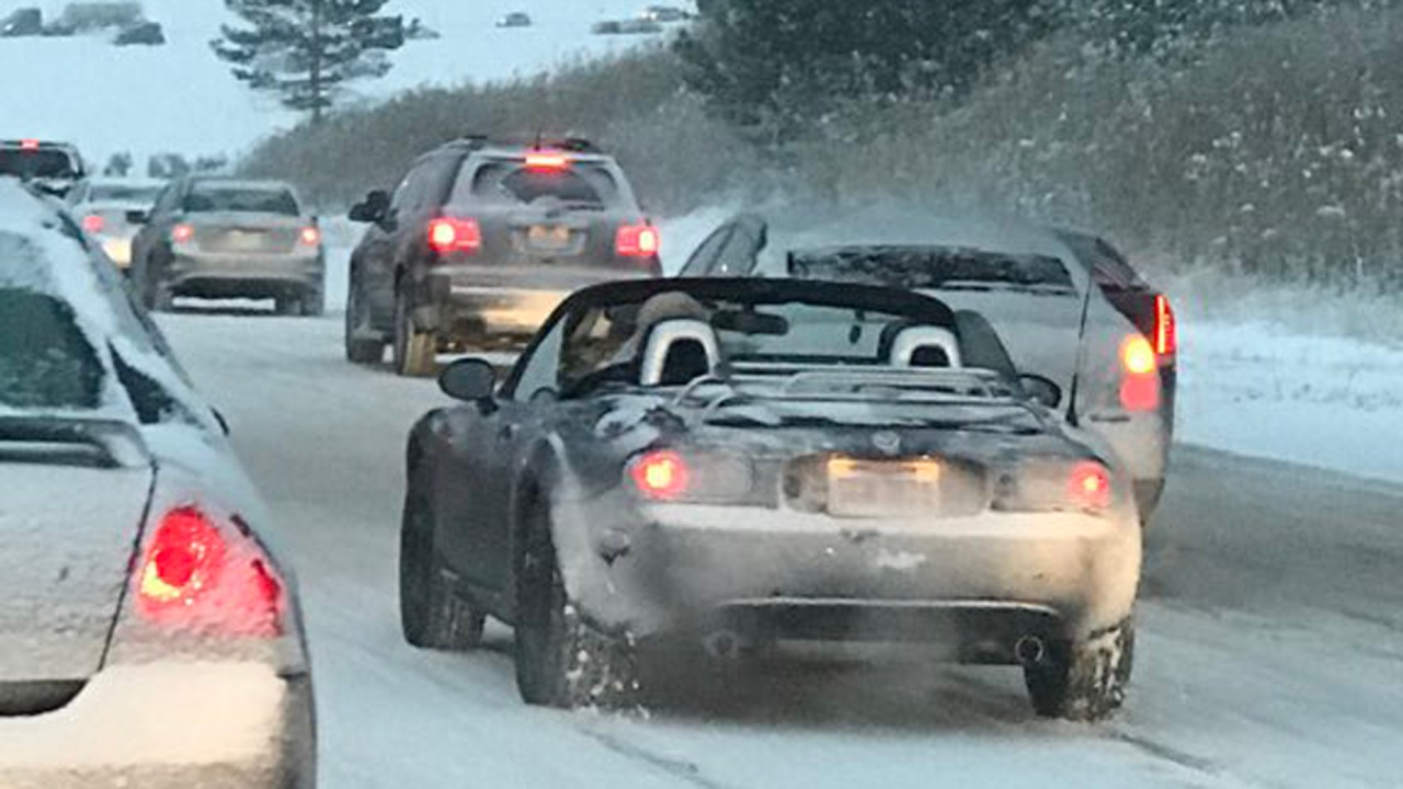 Mazda Miata driving in the snow with the top down