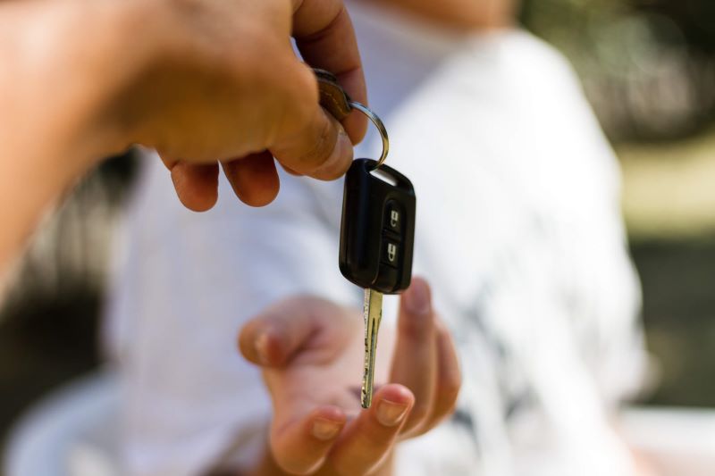 A person handing over a car key to another person.