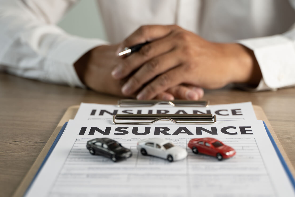 Paperwork that says insurance with little toy cars on it