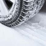 A close up of a tire with an imprint of tire tread in the snow