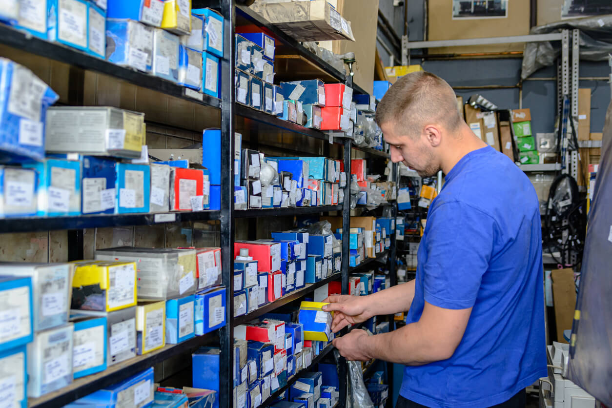 A person looking at shelves full of small car parts in boxes