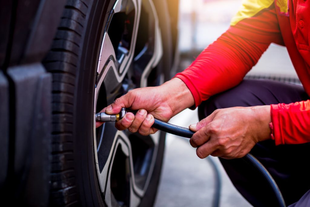 A photo of a person putting air in a car tire.
