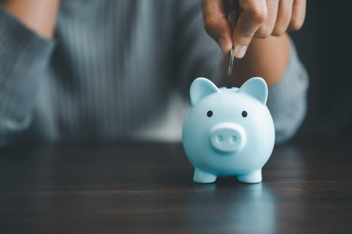 Hand putting money into a piggy bank.