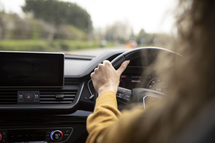 Close-up of female hands on a car steering wheel.